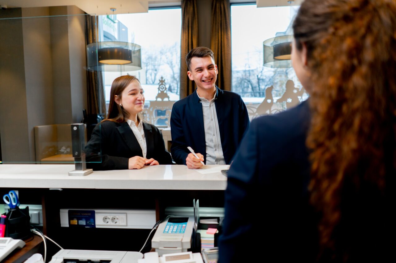 The receptionist at the counter meets guests with luggage in the hotel business travel hospitality
